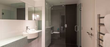 A modern bathroom with a glass-enclosed shower, a white sink, and a mirror.