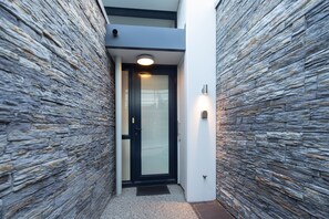 A modern building entrance with a stone facade, a glass door, and a small overhang above the door.