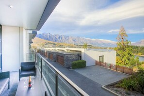 A modern balcony with a view of mountains, a glass railing, and a table with a bottle and glasses. - Panorama Terrace Apartments, Element Escapes (Queenstown)