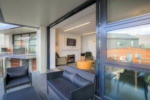 A modern living room with a fireplace, a television, and a glass door leading to an outdoor area.
