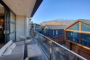 A modern balcony with a glass railing, a sofa, and a table. - Panorama Terrace Apartments, Element Escapes (Queenstown)