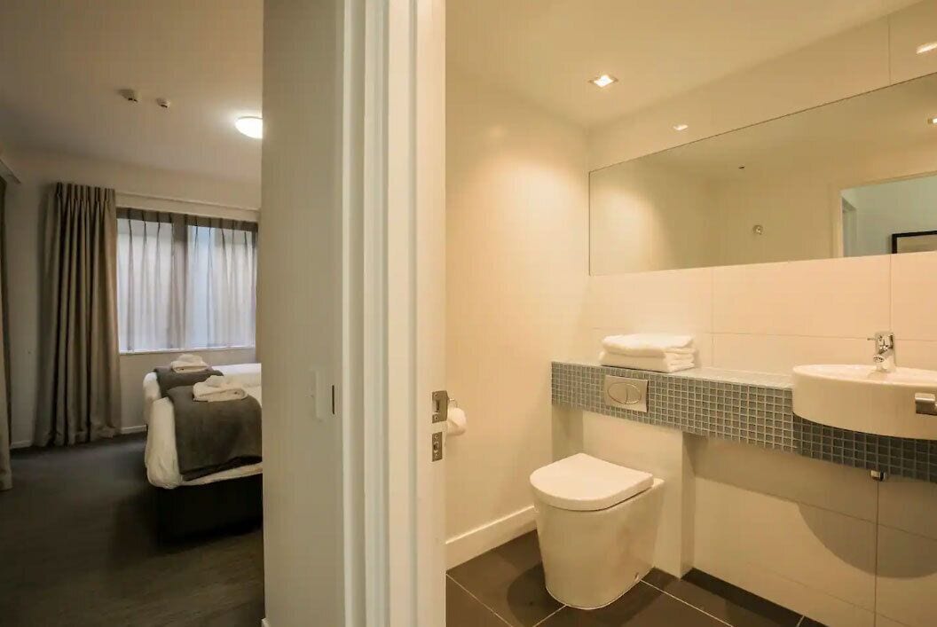 A modern bathroom with a toilet, sink, and mirror.