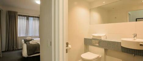 A modern bathroom with a toilet, sink, and mirror.