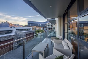 A modern balcony with a glass railing, a white sofa, and a small table.