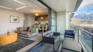 A modern living room with a sofa, a coffee table, and a balcony with a view of mountains. - Panorama Terrace Apartments, Element Escapes (Queenstown)
