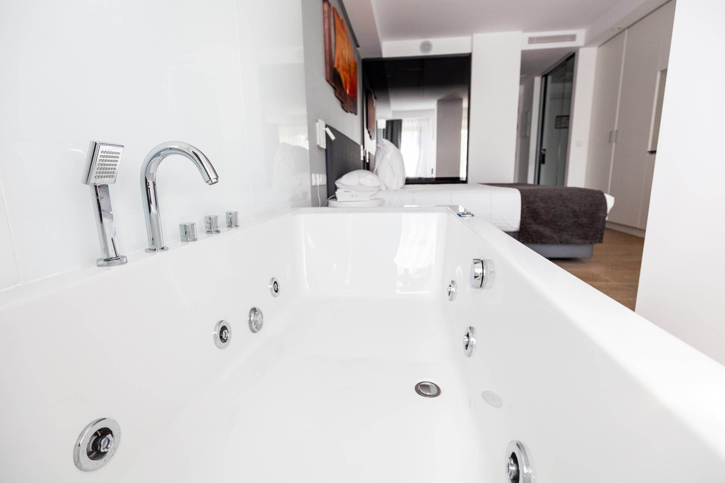 Une salle de bain moderne avec une grande baignoire blanche, un robinet chromé et plusieurs pommes de douche.