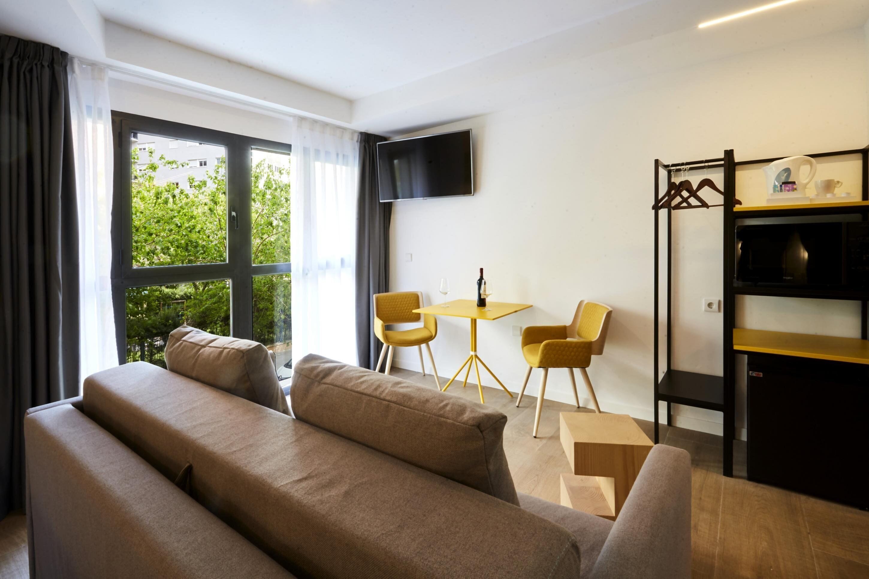 Una sala moderna con un sofá, dos sillones, una mesa de centro y un televisor de pantalla plana montado en la pared.