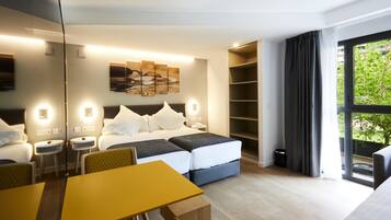A modern hotel room with a bed, bedside tables, a desk, and a large window with curtains.