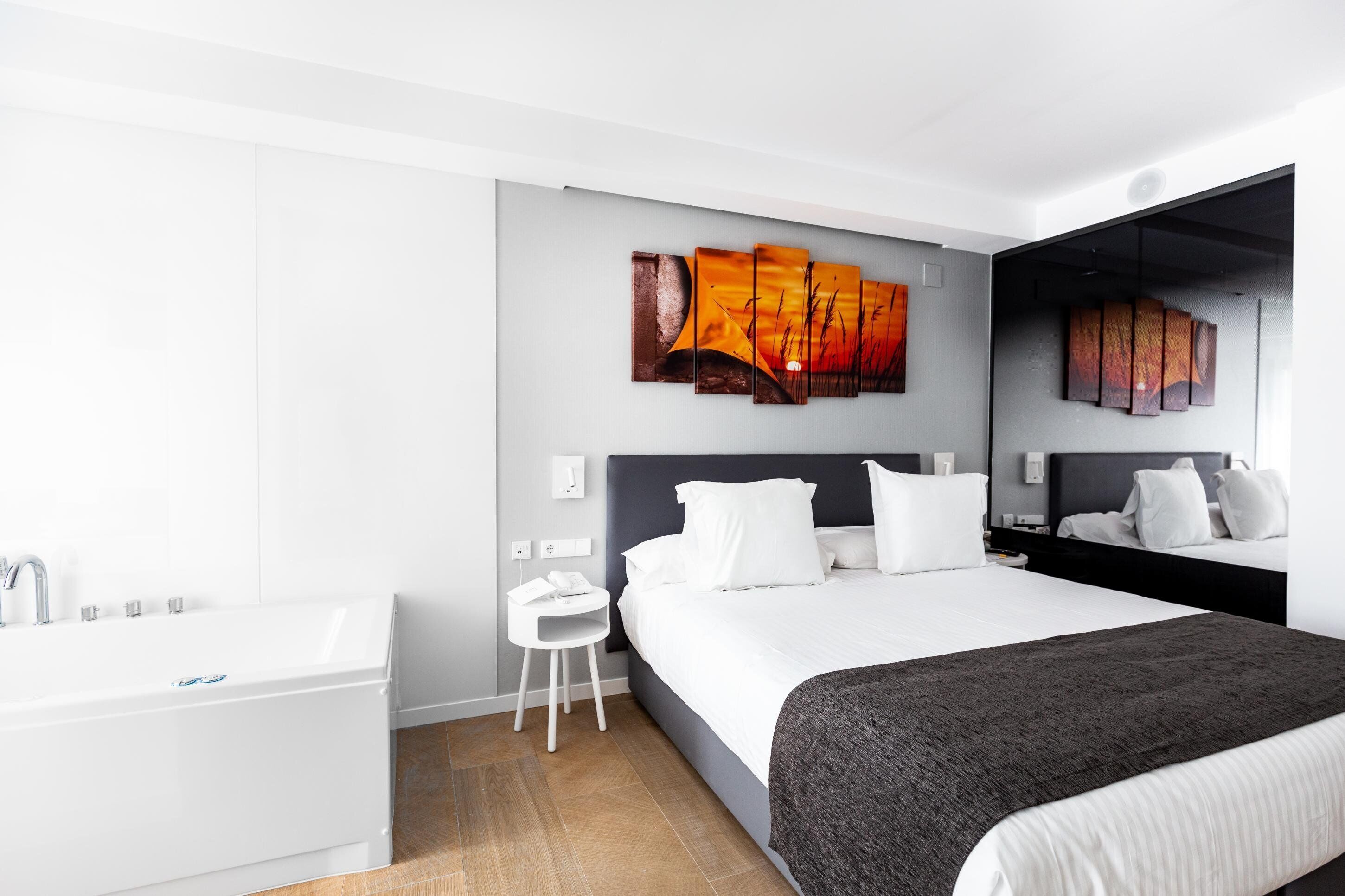 Una habitación de hotel moderna con una cama grande, baño separado y un cuadro en la pared.
