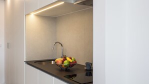 A modern kitchen with a stainless steel sink, a bowl of fruit, and a smartphone on the countertop. - Moontels Valencia Alameda 41 (Valencia)