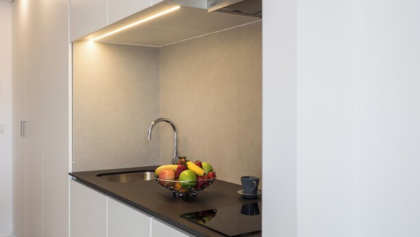 A modern kitchen with a stainless steel sink, a bowl of fruit, and a smartphone on the countertop. - Moontels Valencia Alameda 41 (Valencia)