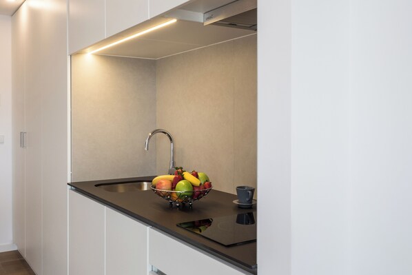A modern kitchen with a stainless steel sink, a bowl of fruit, and a smartphone on the countertop. - Moontels Valencia Alameda 41 (Valencia)