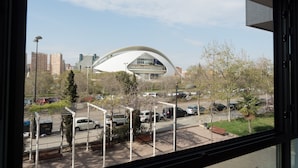A view of a modern building with a unique curved roof, surrounded by a parking lot and trees. - Moontels Valencia Alameda 41 (Valencia)