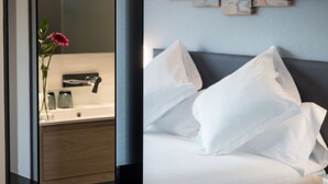 A modern bathroom with a wooden vanity, a white sink, and a vase with a pink flower. - Moontels Valencia Alameda 41 (Valencia)