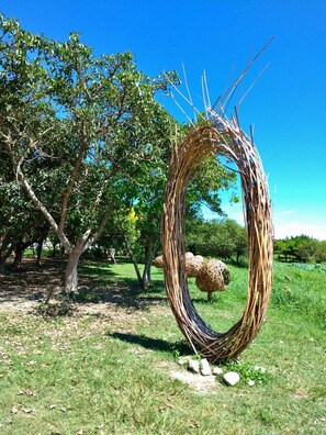 A circular wicker structure in a park with trees and grass. - Vineyard Guest House (Taitung)