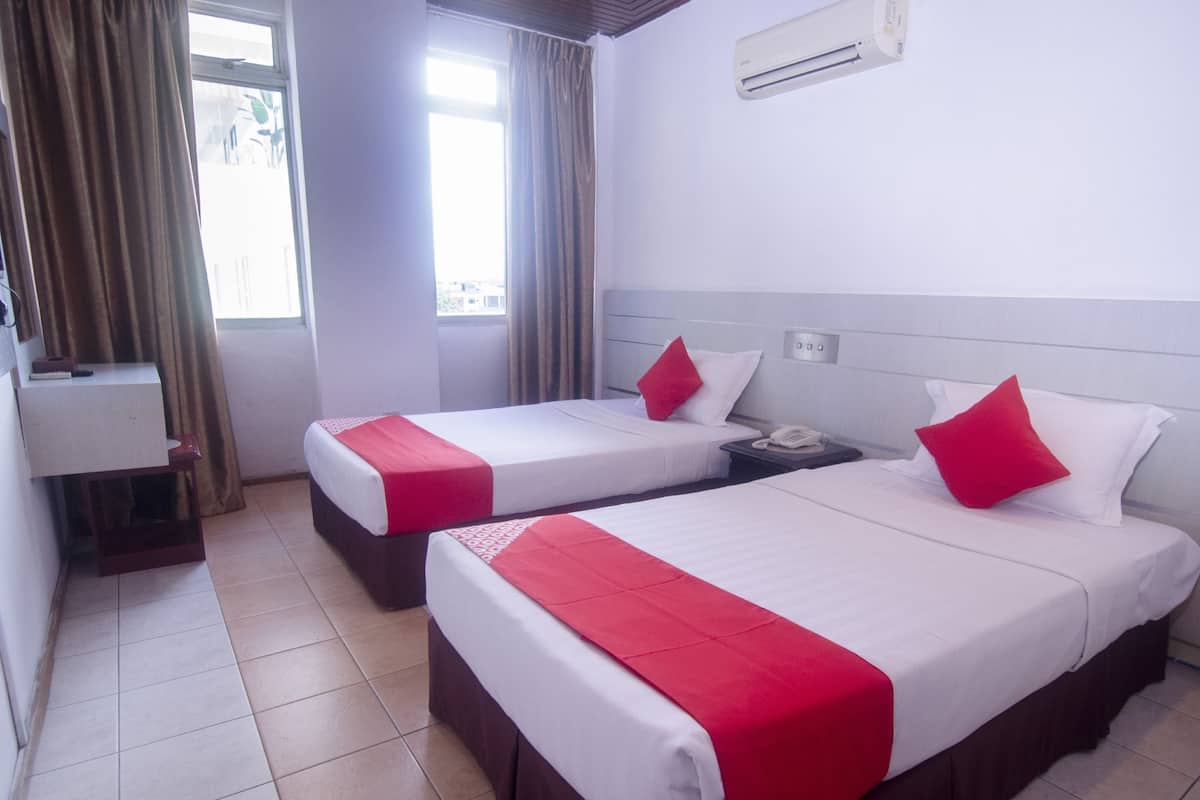 A hotel room with two beds, a desk, and a window with curtains.