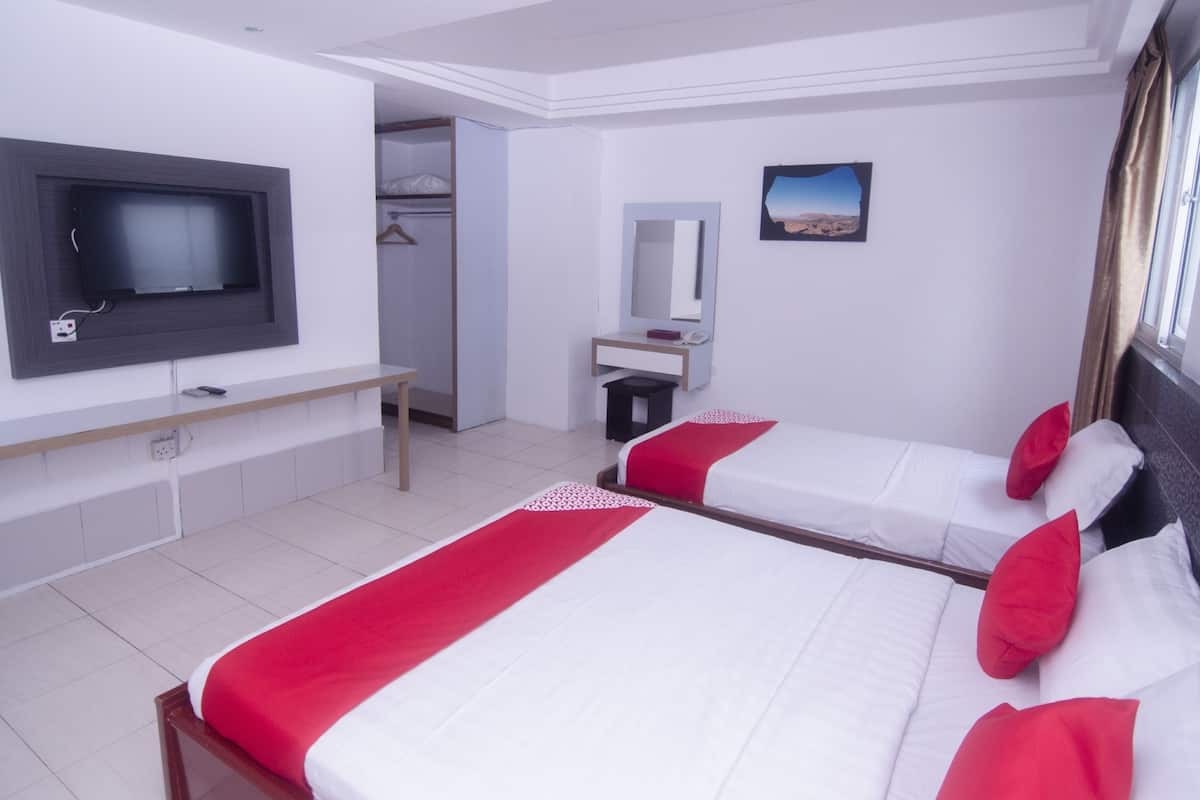 A hotel room with two beds, a TV, a desk, a mirror, and a wardrobe.