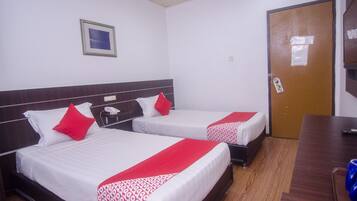 A hotel room with two beds, a wooden headboard, a small bedside table with a phone, and a door with a lock.