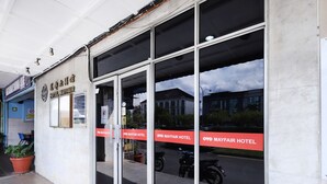 The exterior of OYO Mayfair Hotel with large glass doors, a signboard, and a potted plant. - Hotel O yfair Hotel (Kuching)