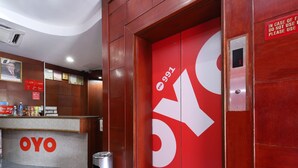 A reception area with a red door marked "OYO" and an elevator with a digital display. - Hotel O yfair Hotel (Kuching)