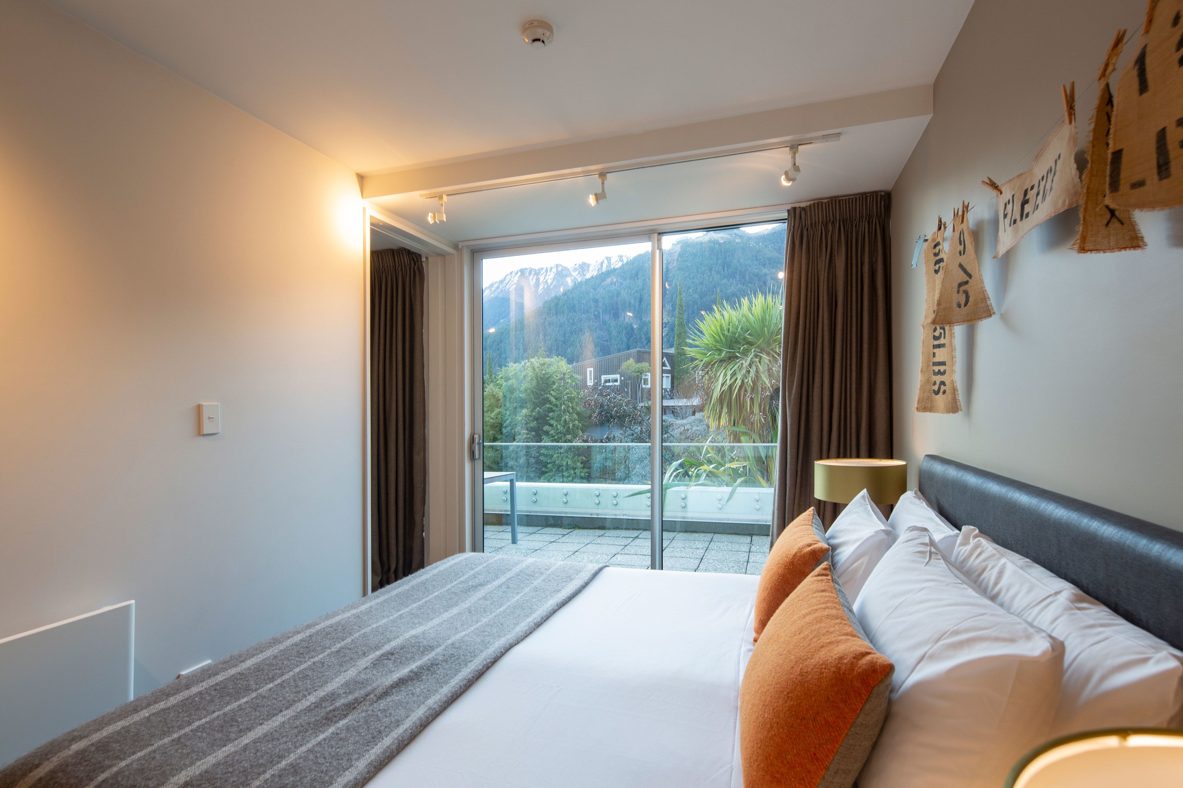 A hotel room with a large bed, a view of a balcony, and a mountain in the background.