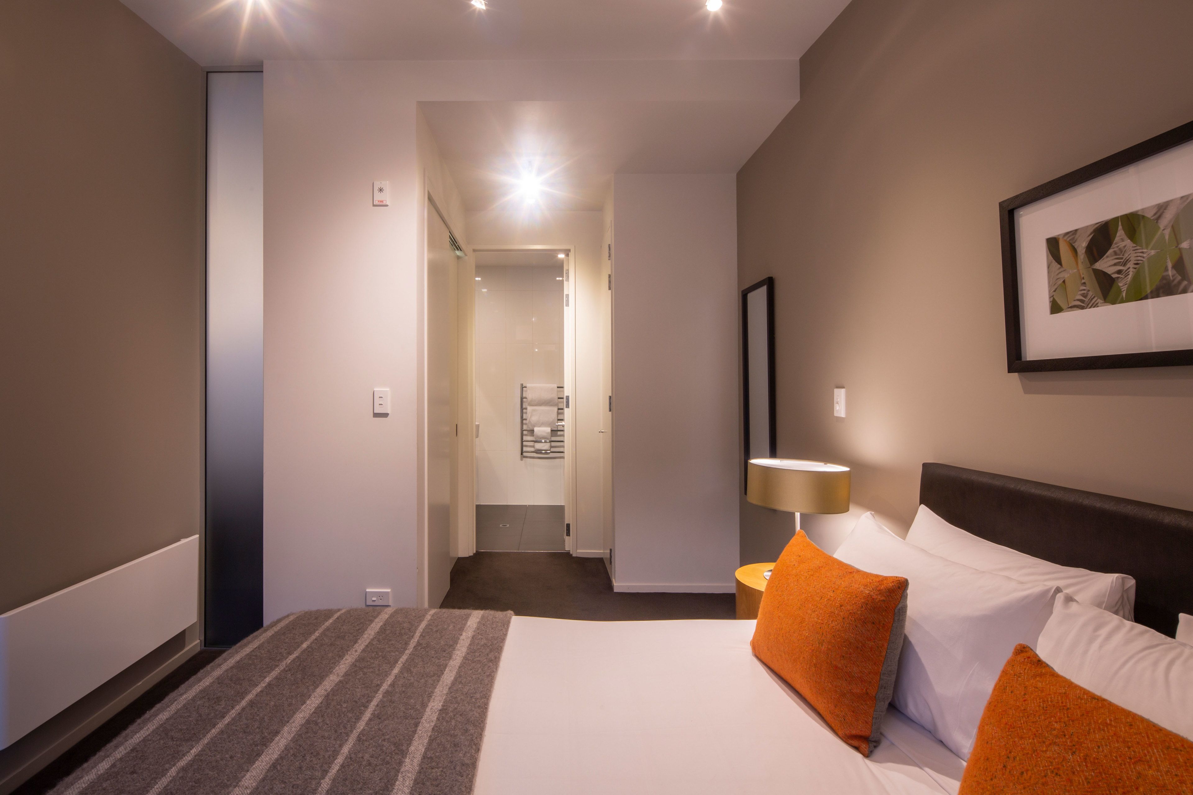 Une chambre d’hôtel avec un lit, une table de chevet, une lampe et un tableau encadré au mur.