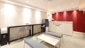 A hotel reception area with a reception desk, chairs, a bench, and a trash bin. - Browndot Hotel Centum City Bexco (Busan)