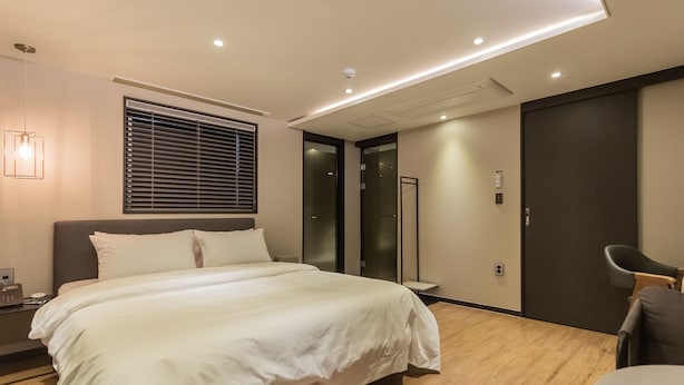A modern hotel room with a large bed, a bedside table, a lamp, a sliding door, and a chair. - Browndot Hotel Centum City Bexco (Busan)