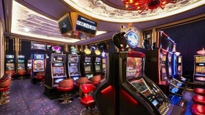 A casino interior with slot machines, red bar stools, and a ceiling with a large, illuminated design. - Browndot Hotel Centum City Bexco (Busan)