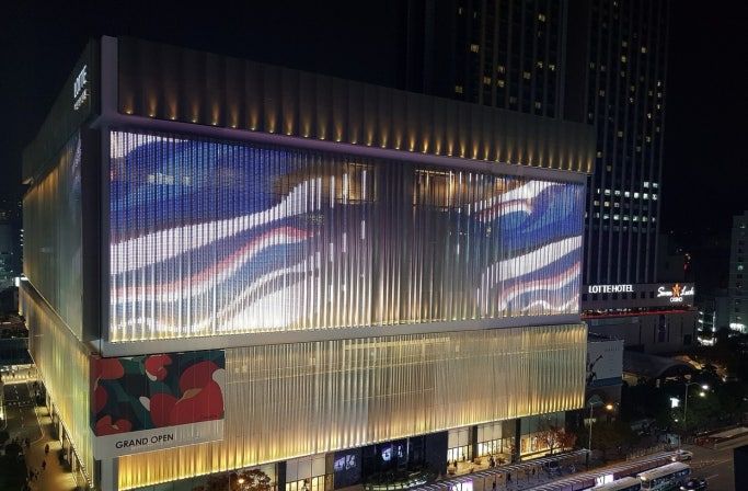 A modern hotel with a large digital display on the facade, a covered outdoor area, and a visible entrance.