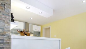 A modern kitchen with two bar stools, a white countertop, and a stone accent wall.