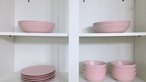 En vit hylla med rosa skålar och tallrikar.