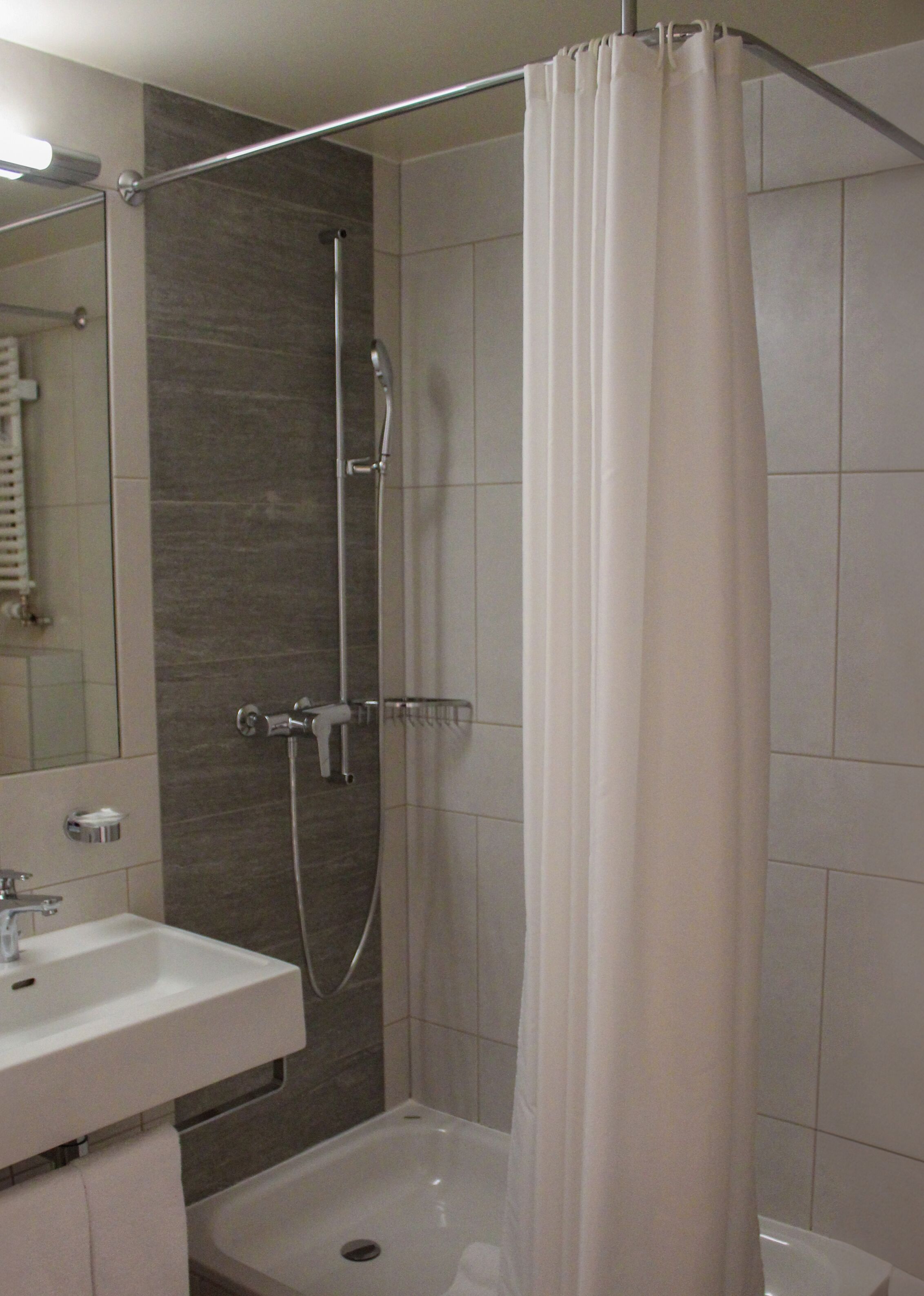 A modern bathroom with a shower, a sink, and a mirror.