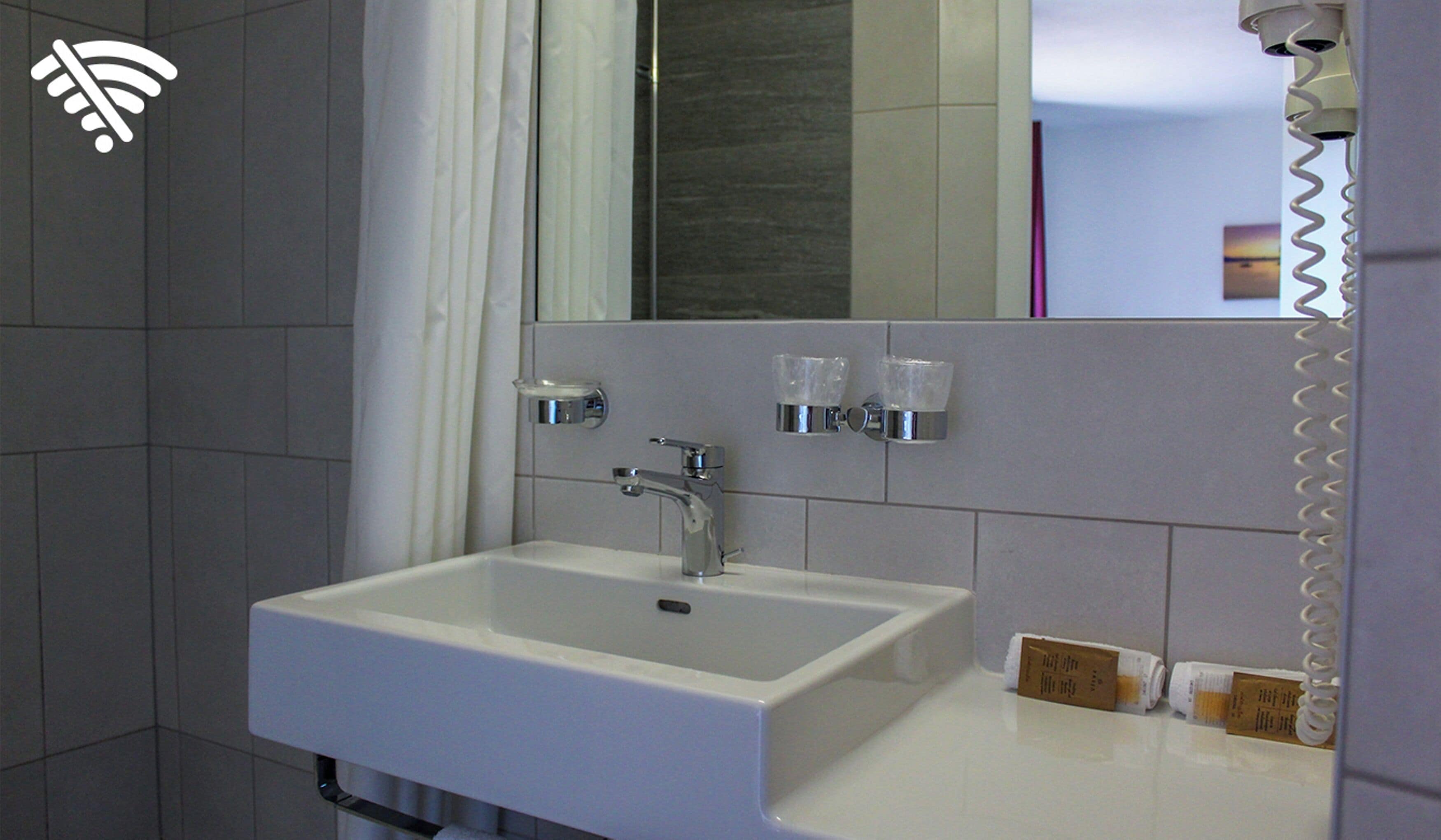 Un baño con lavamanos blanco, espejo y cortina de ducha.