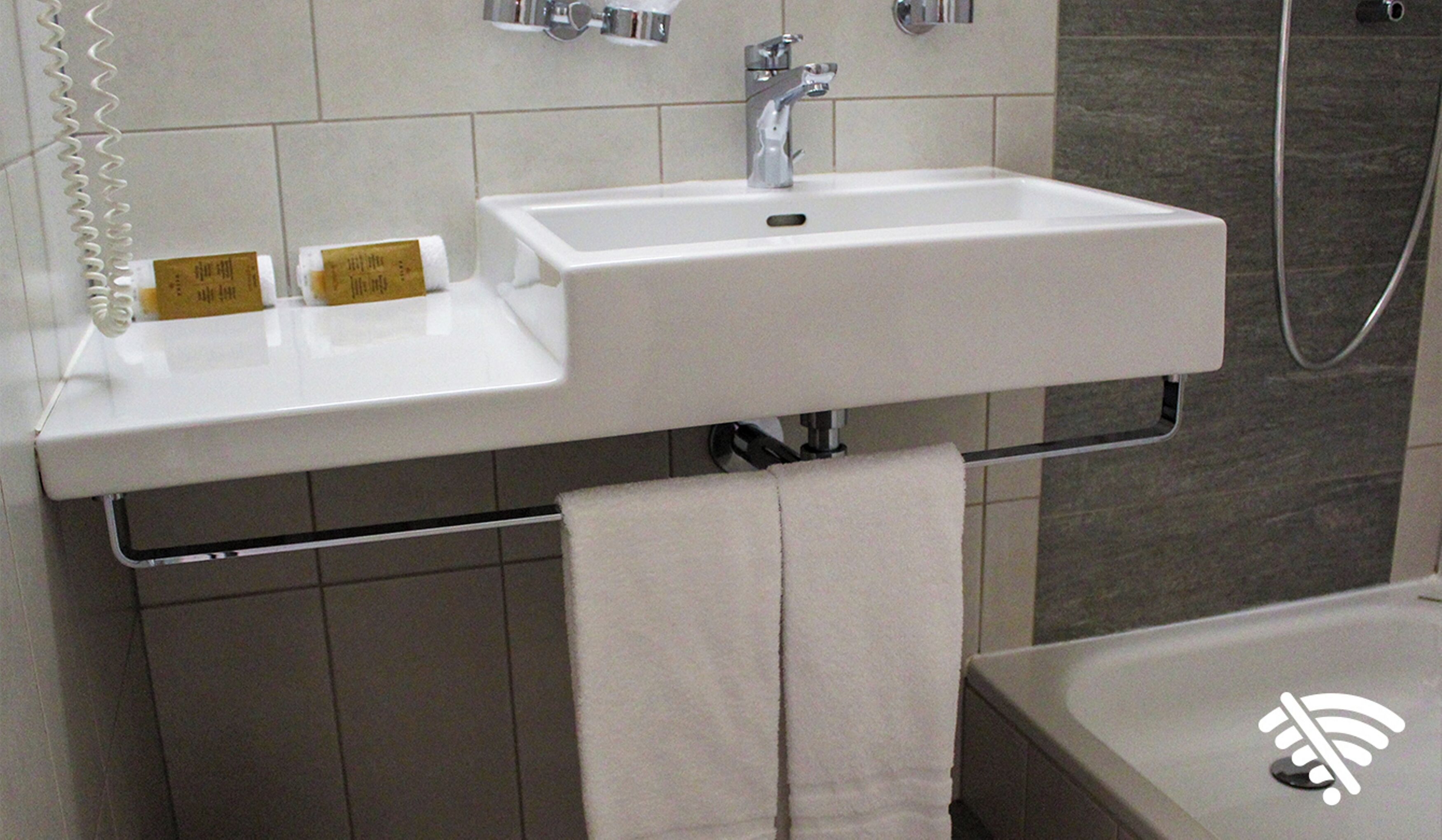 A bathroom with a white sink, a towel rack, and a shower.