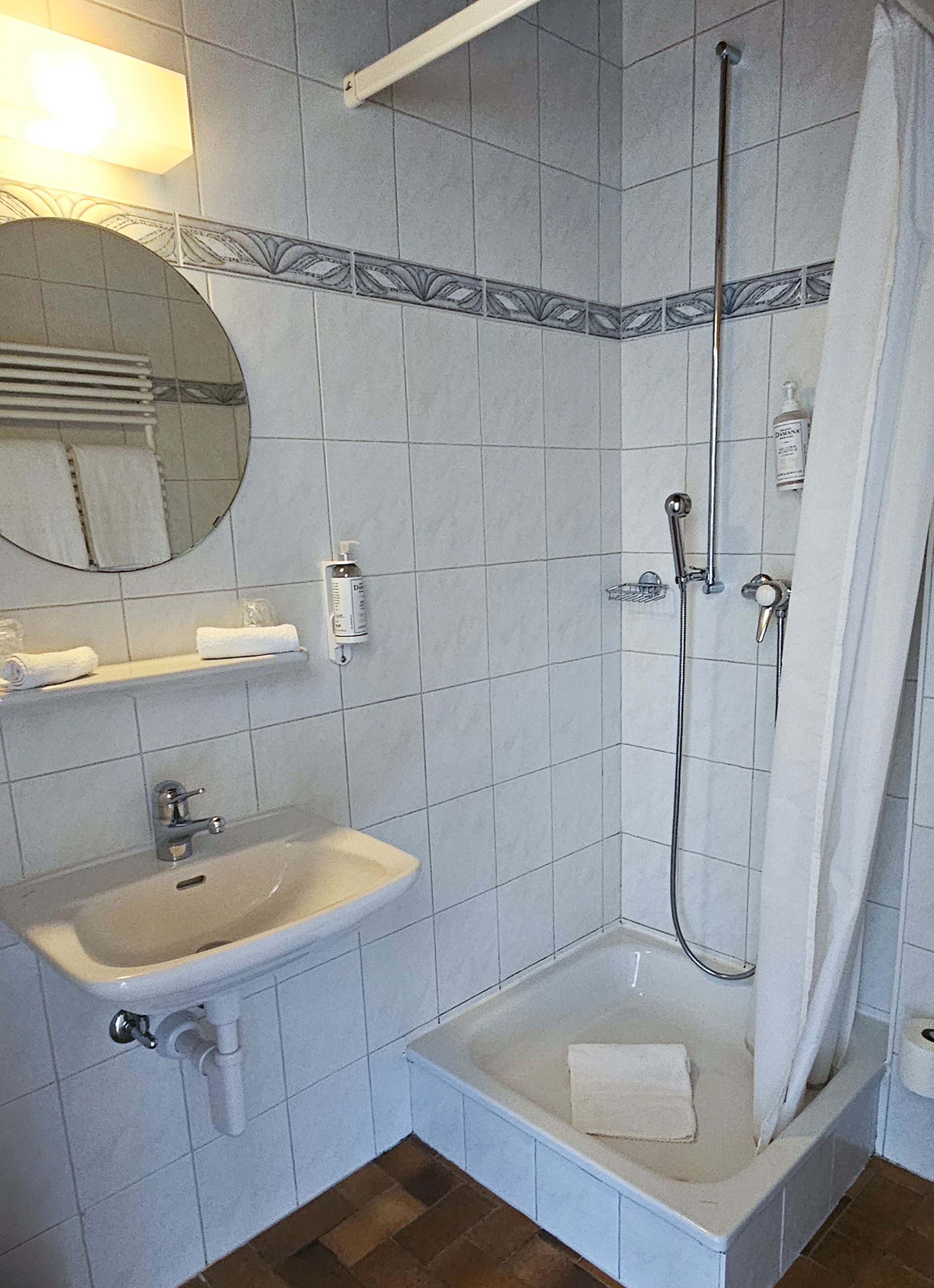 A bathroom with a sink, mirror, and shower.
