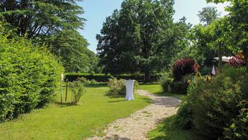 Un sendero en un jardín que lleva a una estructura blanca, rodeada de abundante vegetación y árboles.