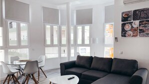 A modern living room with a grey sectional sofa, a round coffee table, and a dining area with a glass table and chairs. - ALICANTE CENTER APART THE PENTHOUSE WITH TERRACE (Alicante (Alacant))