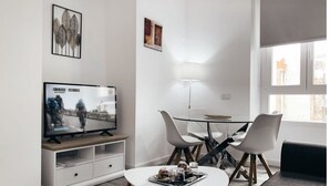 A modern living room with a flat-screen TV, a glass dining table, and two white chairs. - ALICANTE CENTER APART THE PENTHOUSE WITH TERRACE (Alicante (Alacant))