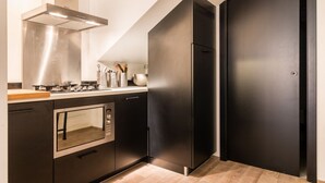 Una cocina moderna con horno empotrado, campana extractora de acero inoxidable y refrigerador negro.