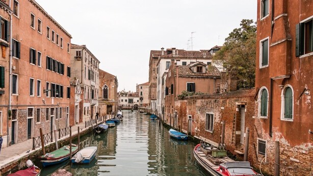 Un canal estrecho bordeado por edificios históricos con barcos amarrados a los lados.