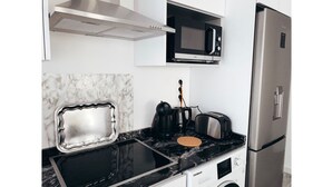 A modern kitchen with a stainless steel refrigerator, a microwave, a kettle, and a toaster.