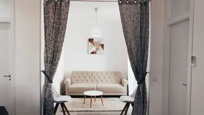 A living room with a sofa, two chairs, a small round table, a white rug, and a pendant light.