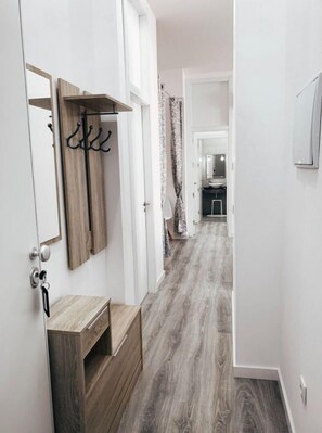 Enter a well-appointed hallway with a bench and coat rack, leading to a bathroom with a mirror and sink.