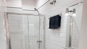 A modern bathroom with a glass-enclosed shower, a white toilet, a sink, and a mirror.