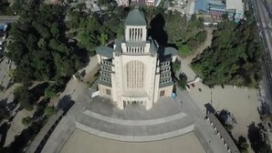 Un grande edificio a più piani con una cupola centrale e ali simmetriche, immerso nel verde.