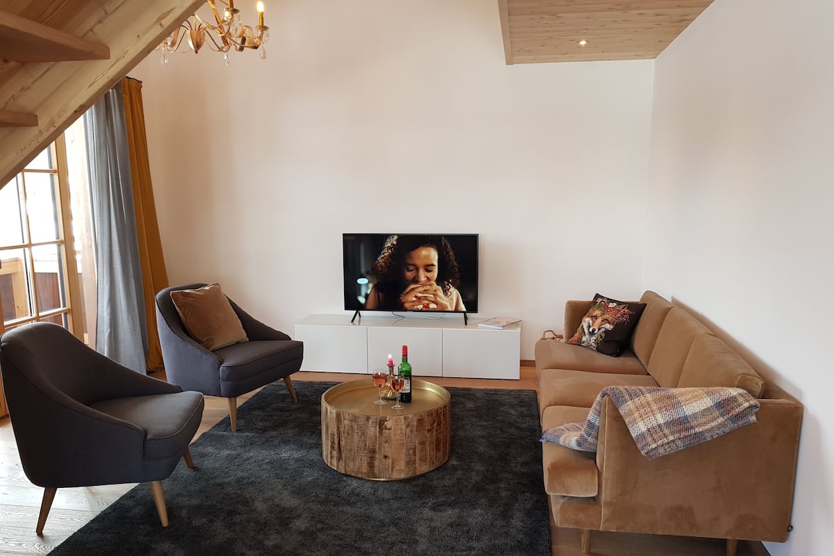 A modern living room with a TV, two sofas, a coffee table, and a wooden ceiling.