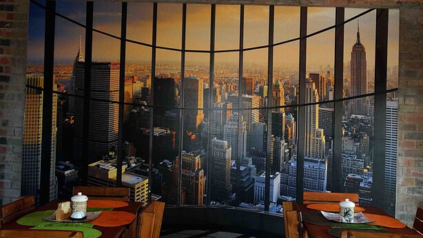 Una habitación con un ventanal grande que da a una vista panorámica de la ciudad, con un edificio de gran altura.
