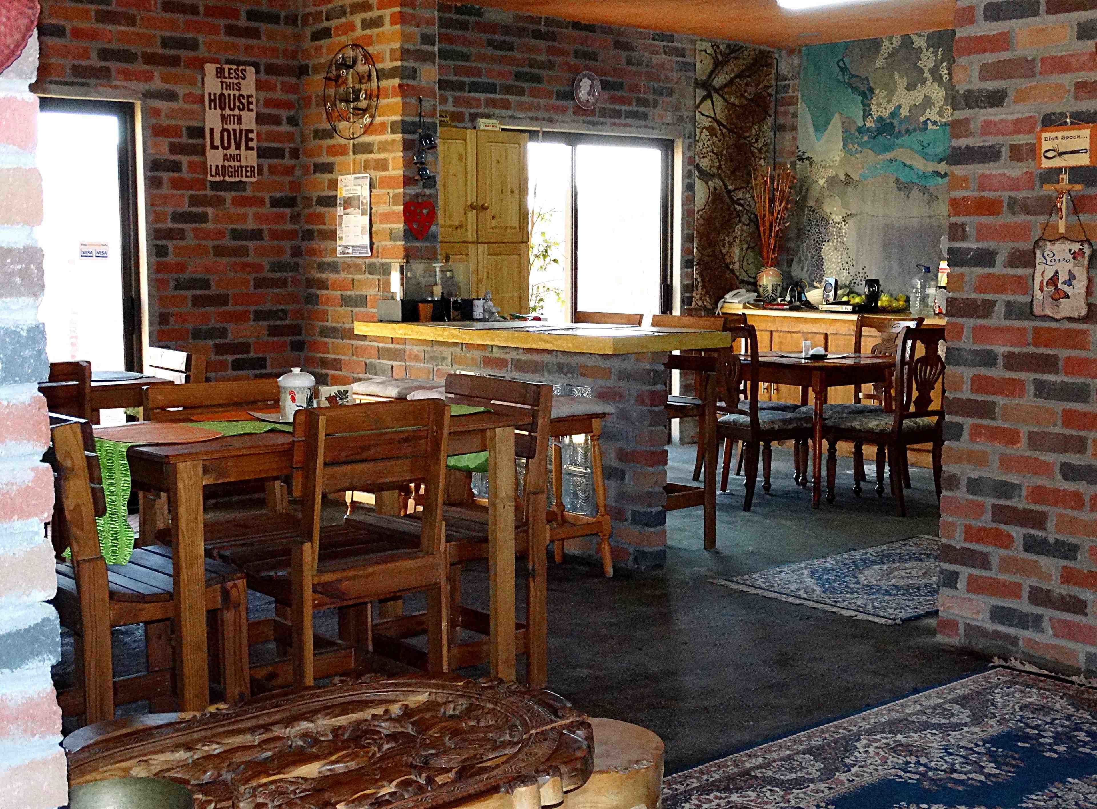 A rustic dining area with brick walls, wooden furniture, and a mural.