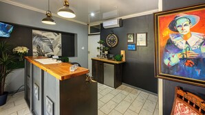 A reception area with a wooden counter, a clock, and a painting on the wall. - Graceland Guest House (Potchefstroom)